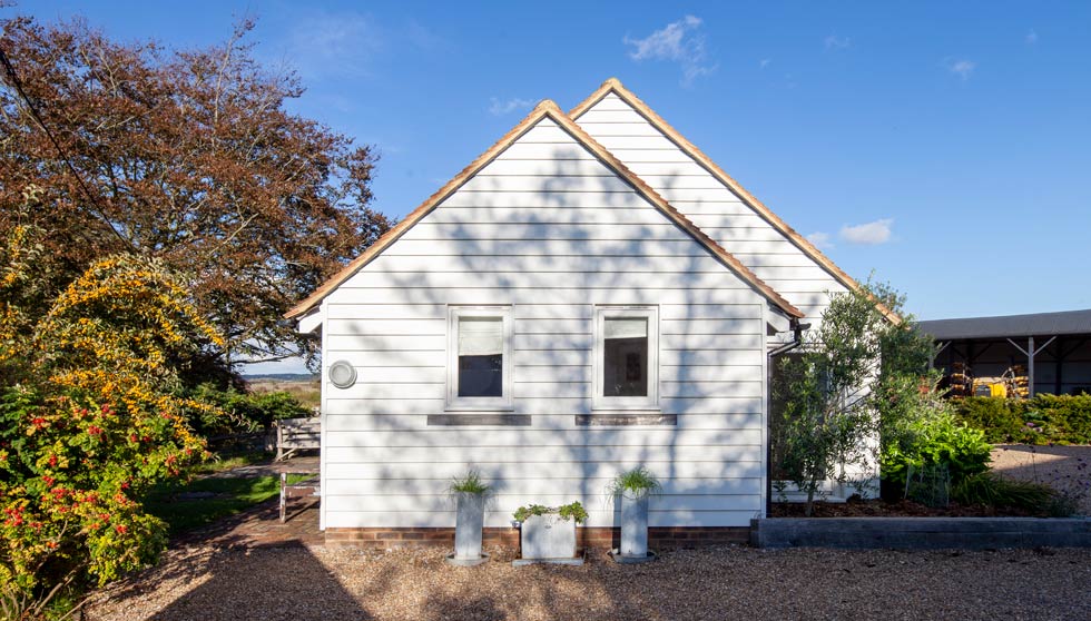 The Little Barn is clad in traditional white weatherboard. The barn has an open plan central space with a wonderful vaulted ceiling and a wood fired stove.